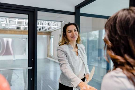 Before stepping into the office rental property, a woman greets a client.