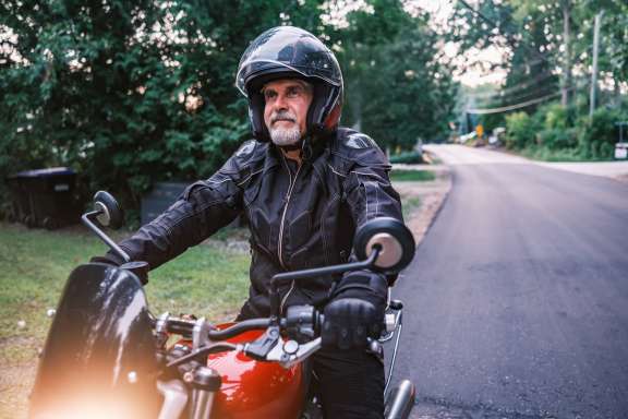 Mature man riding his motorbike in the countryside at dawn