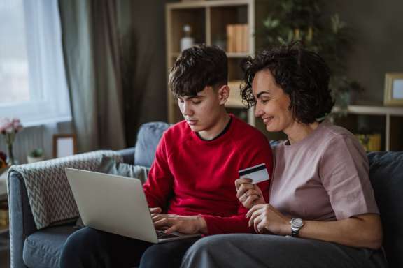Parent helping teen on laptop