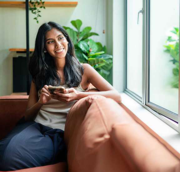 Woman looking out window holding phone