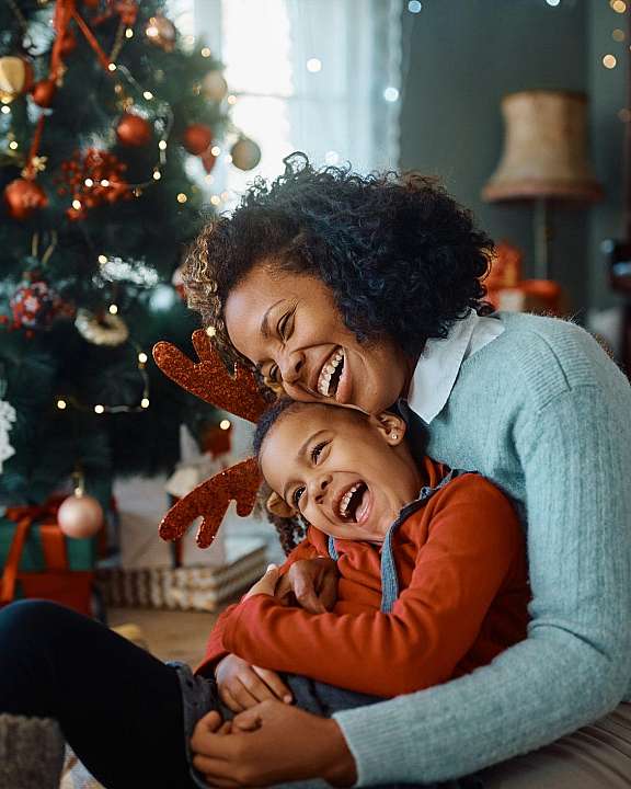 Happy African American mother and daughter laughing and having fun while spending Christmas together at home.